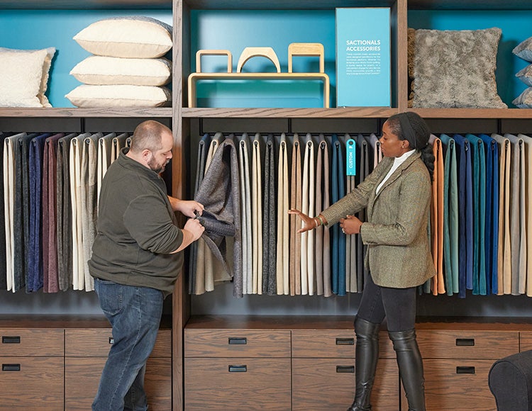 Two people reviewing Lovesac fabric options in a showroom.