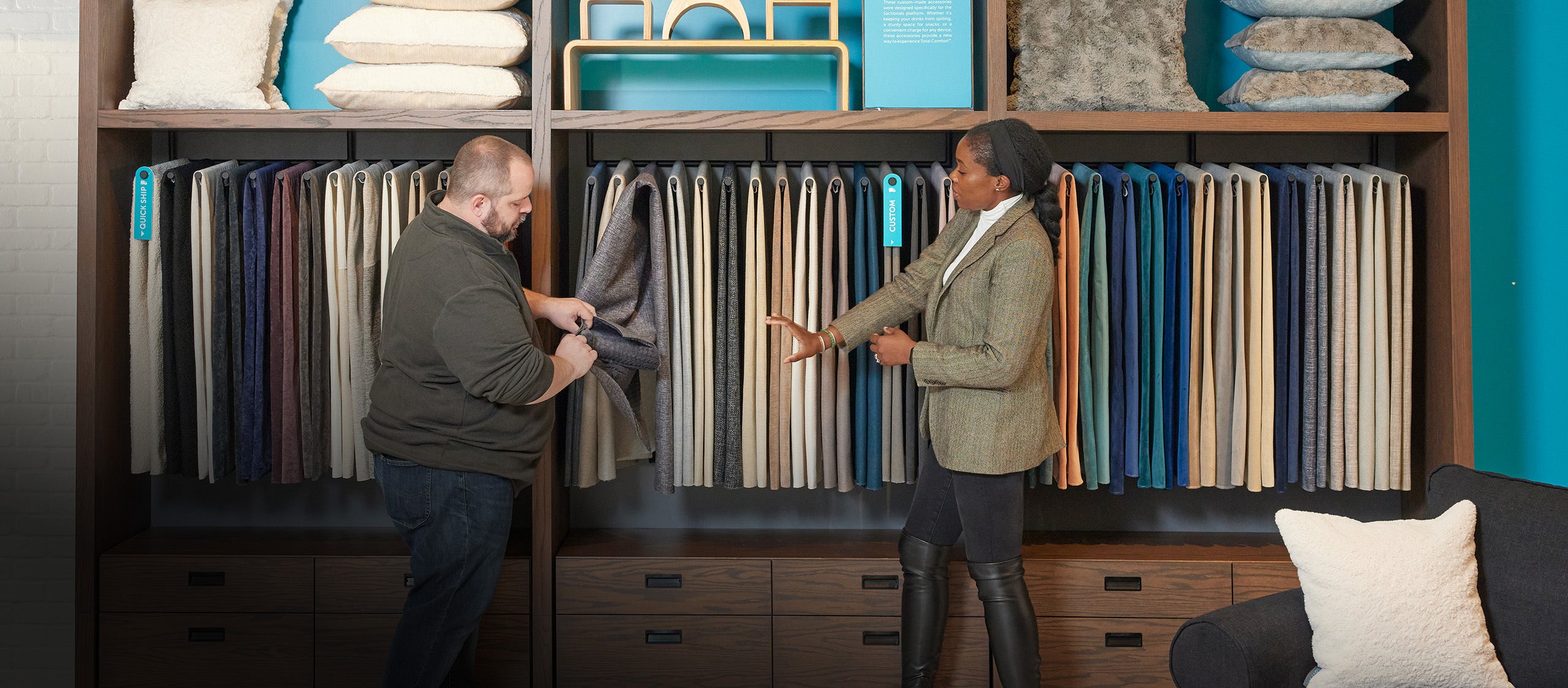 Two people reviewing Lovesac fabric options in a showroom.